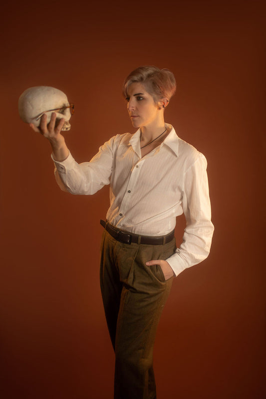 White cotton button up with a tone on tone stripe. Featuring wooden buttons and embroidered latin phrase on the back and cuffs translates to 'finding yourself in the whispers of the world'.