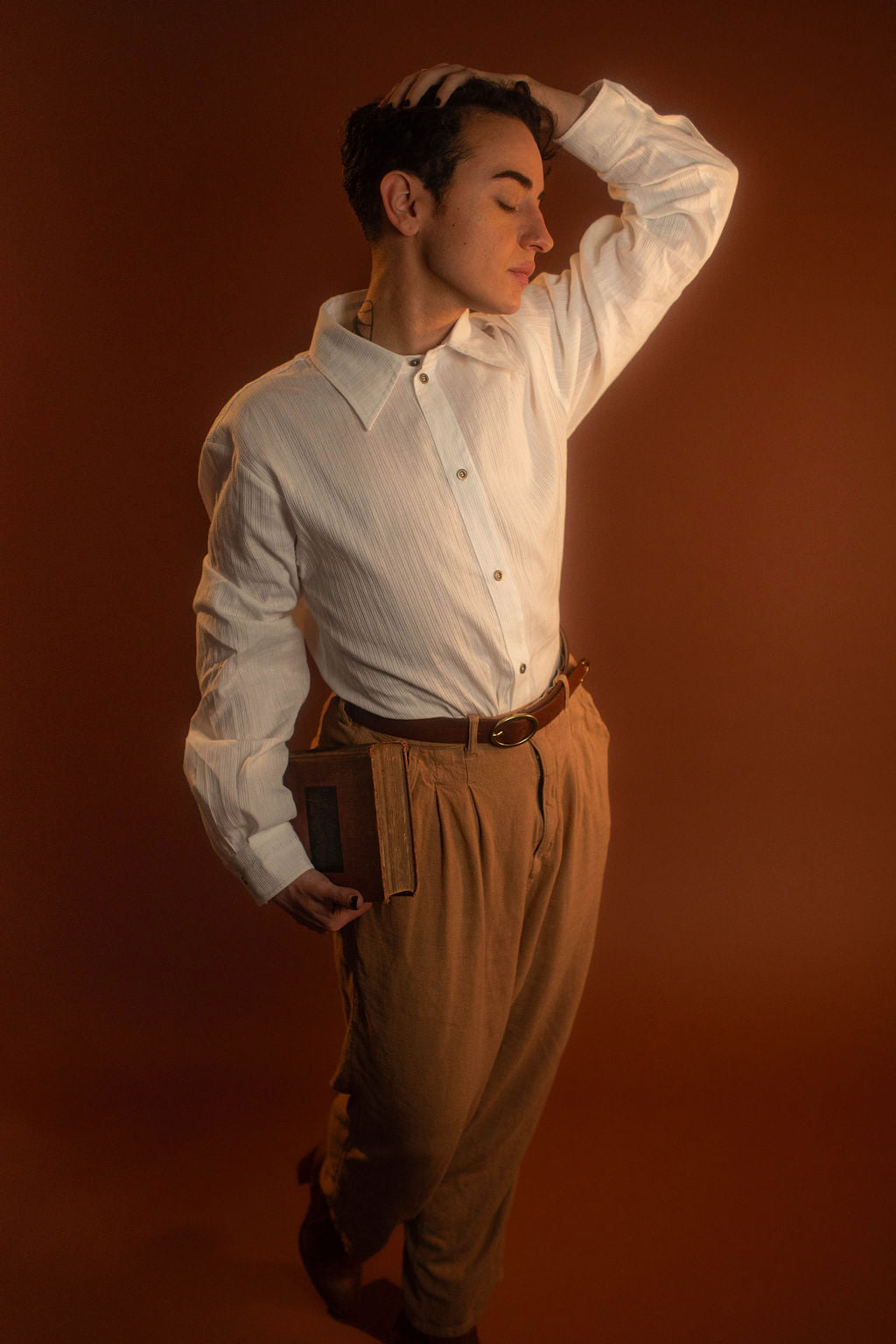 White cotton button up with a tone on tone stripe. Featuring wooden buttons and embroidered latin phrase on the back and cuffs translates to 'finding yourself in the whispers of the world'.