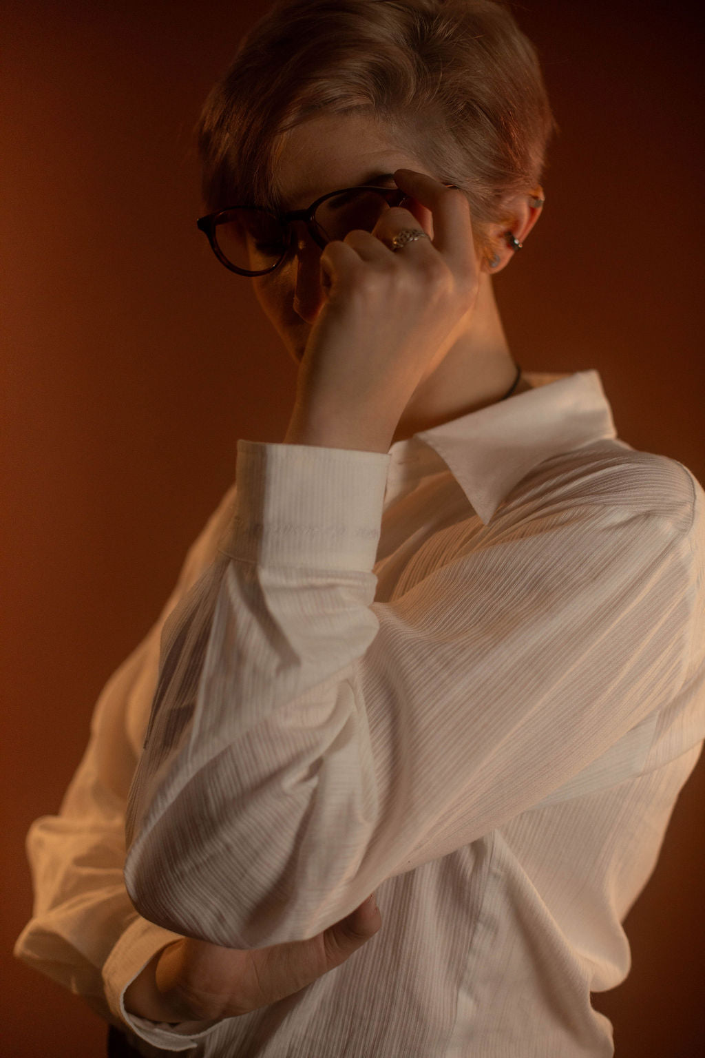 White cotton button up with a tone on tone stripe. Featuring wooden buttons and embroidered latin phrase on the back and cuffs translates to 'finding yourself in the whispers of the world'.