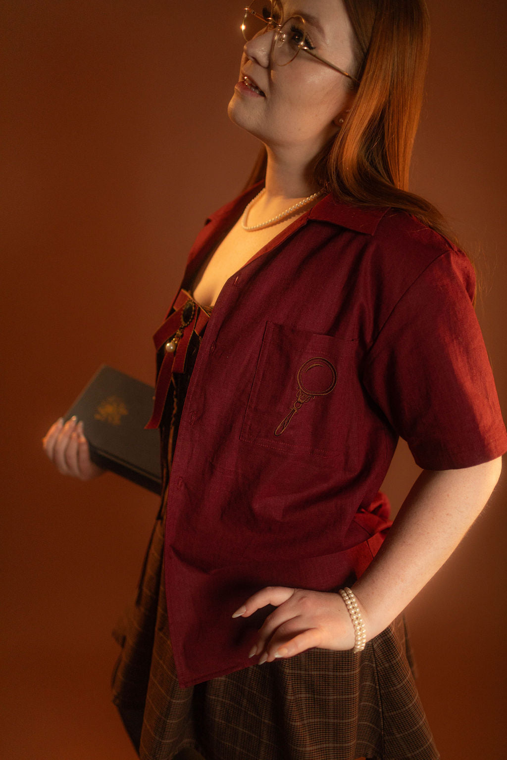 Crisp wine red camp shirt with a linen and cotton blend. With brass brown buttons and a bronze magnifying glass embroidered on the front pocket.