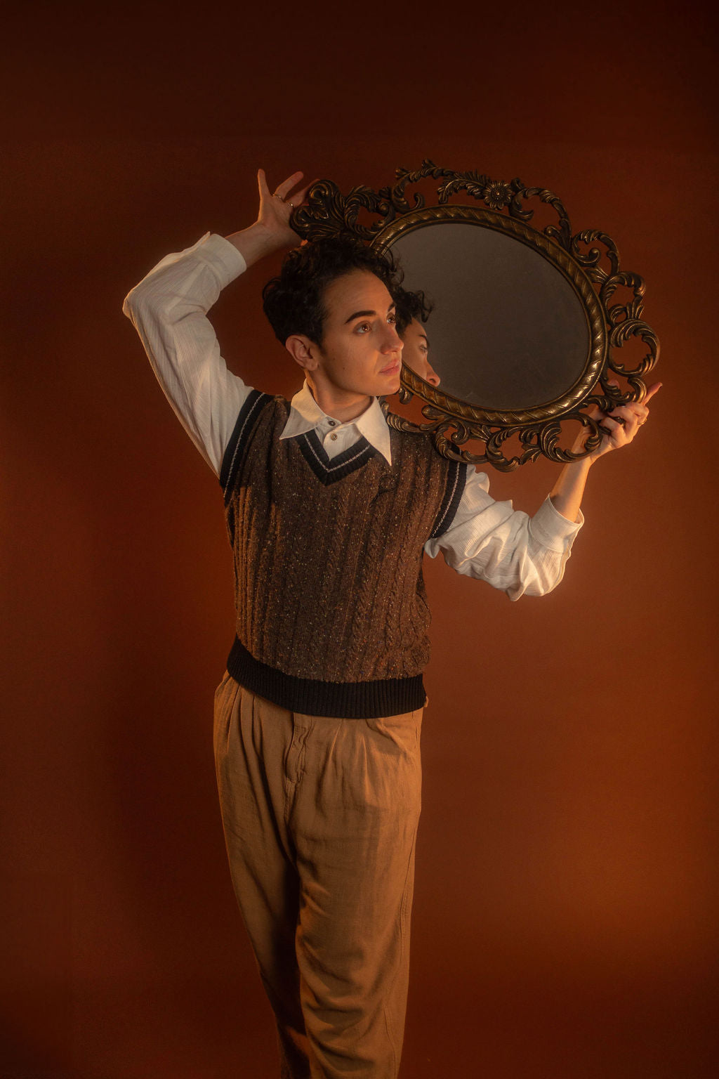 Brown and black wool and nylon blend tweed sweater vest with tennis sweater style black and off-white striped collar and sleeve cuffs. A small, black embroidered magnifying glass on front chest. Featured with our Classics White Button up.