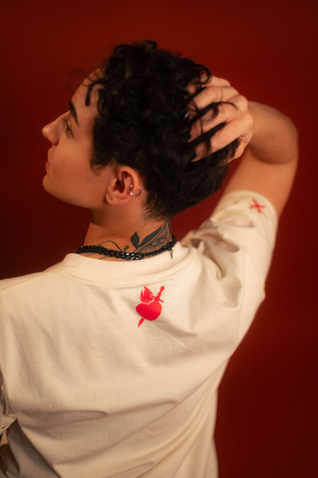 Off-white 100% cotton tshirt with embroidered red sword and heart design on chest, cuffed sleeves with a hand-tacked red X on one, printed collar information, and Saints & Sonnets heart and sword logo on a red hem tag and printed in red on the back collar.