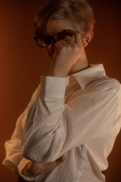 White cotton button up with a tone on tone stripe. Featuring wooden buttons and embroidered latin phrase on the back and cuffs translates to 'finding yourself in the whispers of the world'.