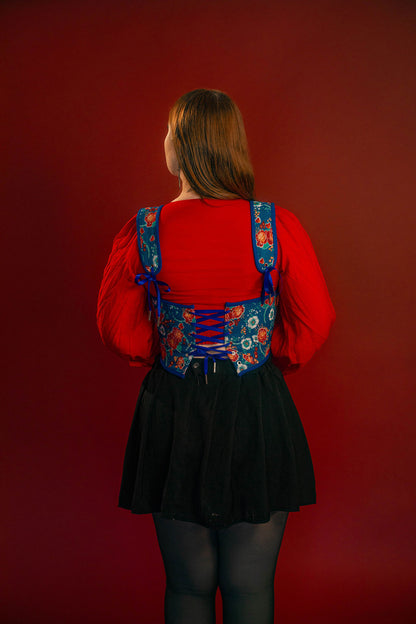 Reversible corset top with floral brocade matching our Montague button up and Lovers Favor bandana on one side and a cobalt blue cotton twill on the other with a printed red, orange, yellow, teal, and silver sacred heart in the middle. Nylon boning for shape, red and blue pairs of satin ribbon to tie removable straps and lace up the back. 