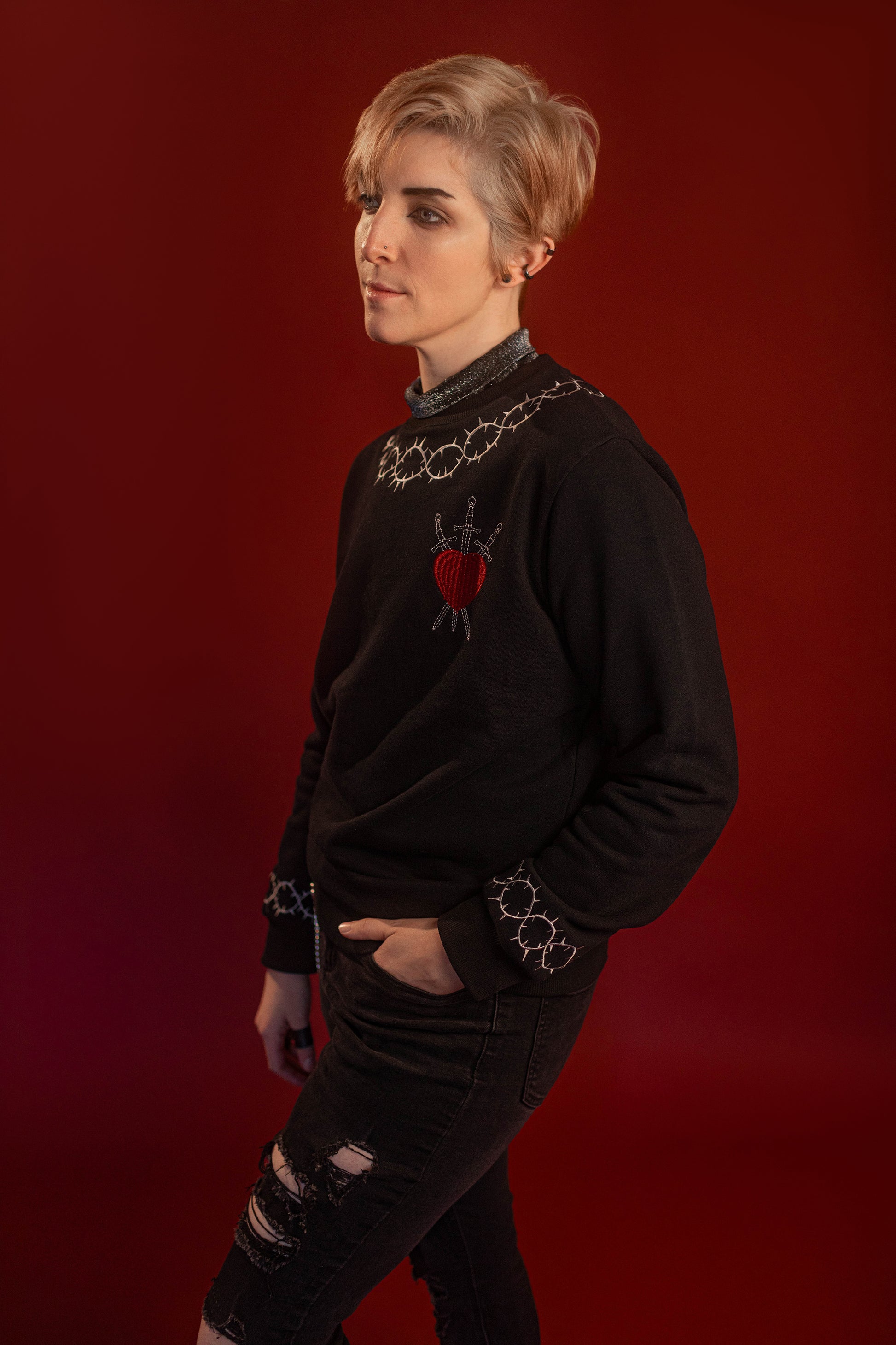 Soft 100% cotton fleece-lined black crewneck sweatshirt. Soft-backed embroidered silver thorn pattern around the collar and cuffs, silver and red three of swords embroidered on chest, with three swords crossed between a red heart. Featured here with our Chainmaille removable Collar dickie.