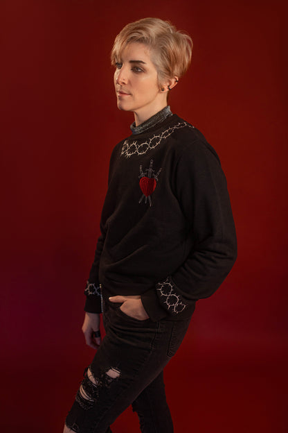 Soft 100% cotton fleece-lined black crewneck sweatshirt. Soft-backed embroidered silver thorn pattern around the collar and cuffs, silver and red three of swords embroidered on chest, with three swords crossed between a red heart. Featured here with our Chainmaille removable Collar dickie.