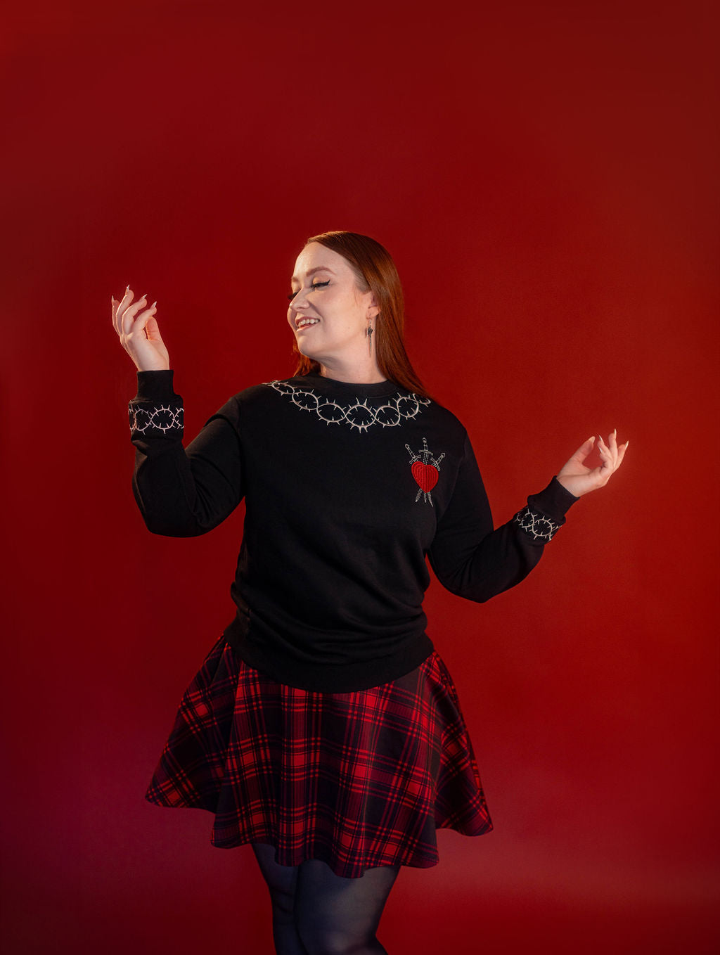 Soft 100% cotton fleece-lined black crewneck sweatshirt. Soft-backed embroidered silver thorn pattern around the collar and cuffs, silver and red three of swords embroidered on chest, with three swords crossed between a red heart.