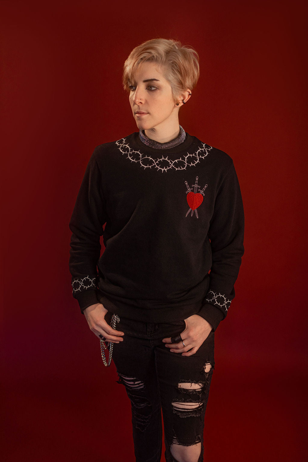 Soft 100% cotton fleece-lined black crewneck sweatshirt. Soft-backed embroidered silver thorn pattern around the collar and cuffs, silver and red three of swords embroidered on chest, with three swords crossed between a red heart. Featured here with our Chainmaille removable Collar dickie.