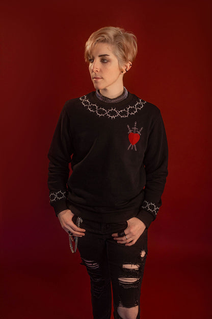 Soft 100% cotton fleece-lined black crewneck sweatshirt. Soft-backed embroidered silver thorn pattern around the collar and cuffs, silver and red three of swords embroidered on chest, with three swords crossed between a red heart. Featured here with our Chainmaille removable Collar dickie.