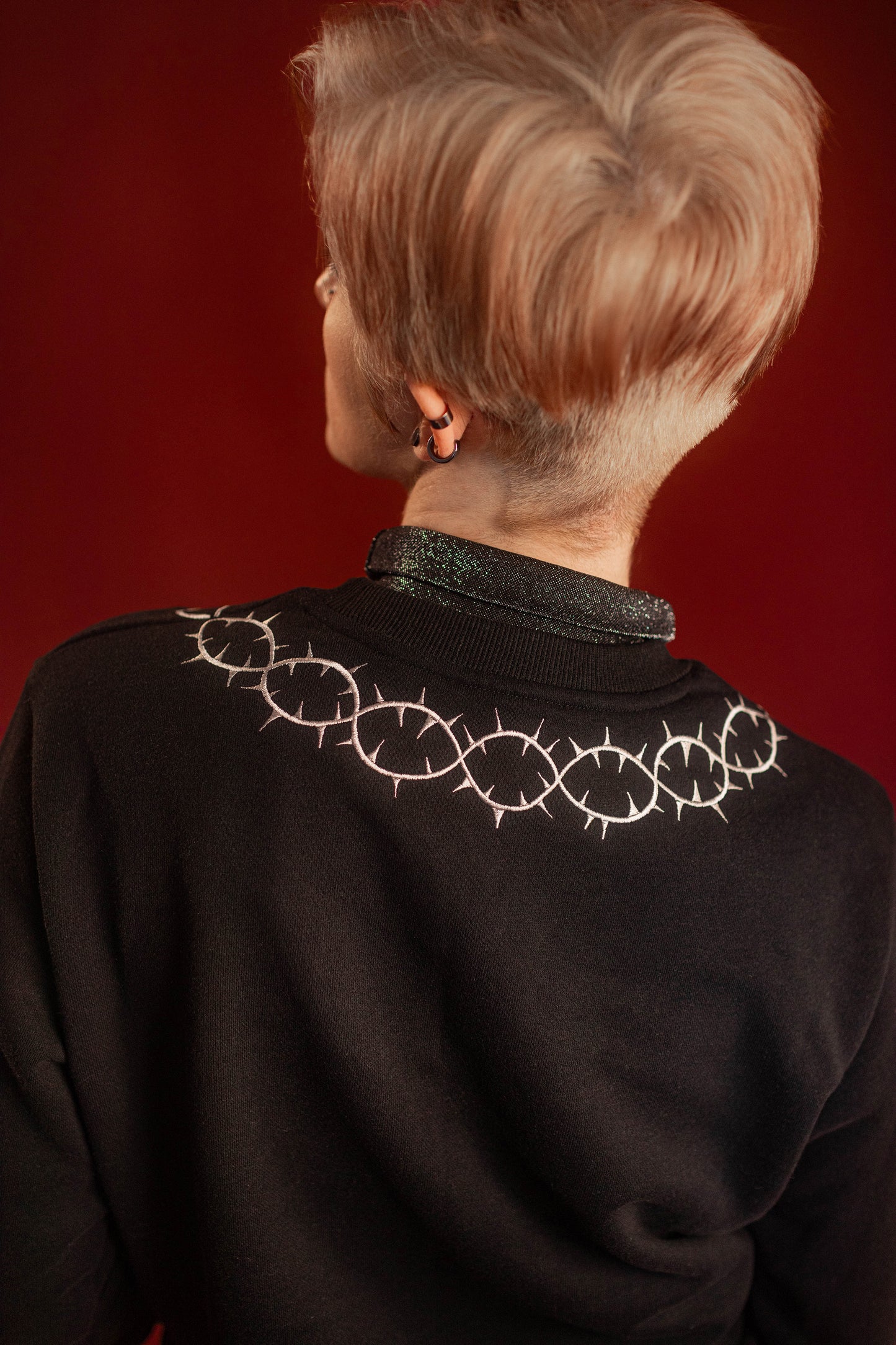 Soft 100% cotton fleece-lined black crewneck sweatshirt. Soft-backed embroidered silver thorn pattern around the collar and cuffs, silver and red three of swords embroidered on chest, with three swords crossed between a red heart. Featured here with our Chainmaille removable Collar dickie.