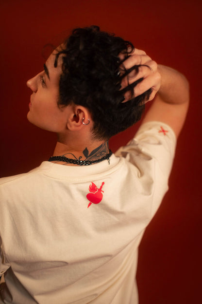 Off-white 100% cotton tshirt with embroidered red sword and heart design on chest, cuffed sleeves with a hand-tacked red X on one, printed collar information, and Saints & Sonnets heart and sword logo on a red hem tag and printed in red on the back collar.
