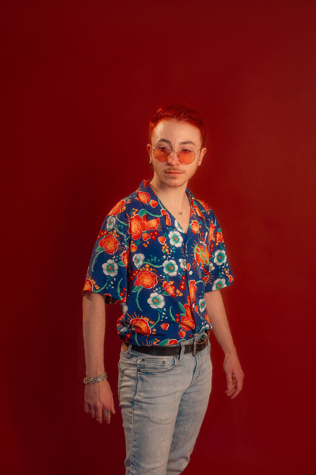 Red, orange, yellow, teal, and blue floral patterned hawaiian style shirt. 100% rayon for a silky feel and drape. Sacred heart graphic with thorn and sword printed on front left chest, and camp style collar. Matches in print and fabric with our Lovers Favor Bandana.