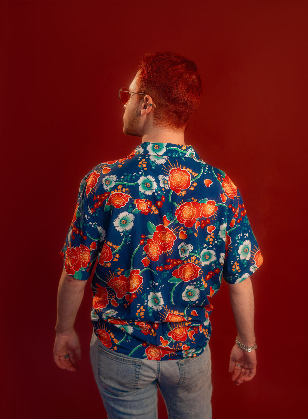 Red, orange, yellow, teal, and blue floral patterned hawaiian style shirt. 100% rayon for a silky feel and drape. Sacred heart graphic with thorn and sword printed on front left chest, and camp style collar. Matches in print and fabric with our Lovers Favor Bandana.