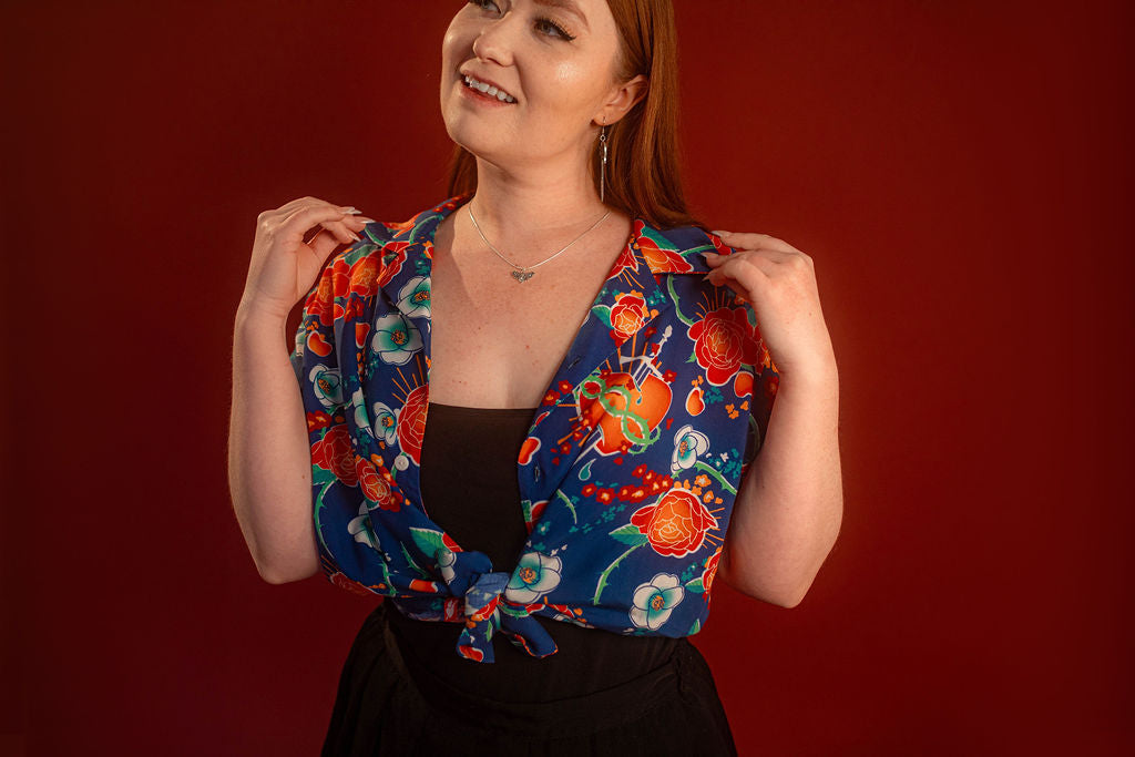Red, orange, yellow, teal, and blue floral patterned hawaiian style shirt. 100% rayon for a silky feel and drape. Sacred heart graphic with thorn and sword printed on front left chest, and camp style collar. Matches in print and fabric with our Lovers Favor Bandana.