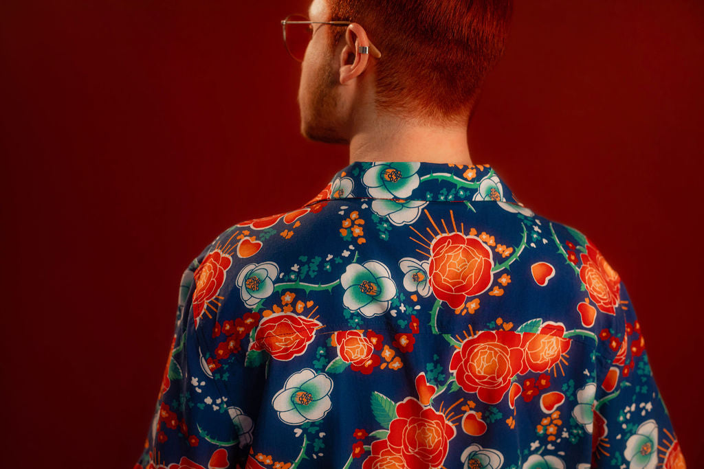 Red, orange, yellow, teal, and blue floral patterned hawaiian style shirt. 100% rayon for a silky feel and drape. Sacred heart graphic with thorn and sword printed on front left chest, and camp style collar. Matches in print and fabric with our Lovers Favor Bandana.