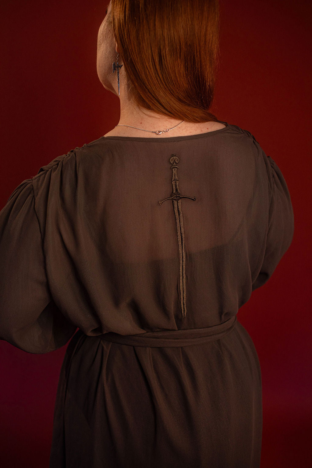 Soft, polyester grey and silver chiffon layered into a sheer, knee-length robe wrap dress. Features a tone-on-tone embroidered sword down the back, and two embroidered on a matching detachable waist tie.