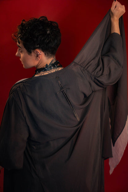 Soft, polyester grey and silver chiffon layered into a sheer, knee-length robe wrap dress. Features a tone-on-tone embroidered sword down the back, and two embroidered on a matching detachable waist tie.