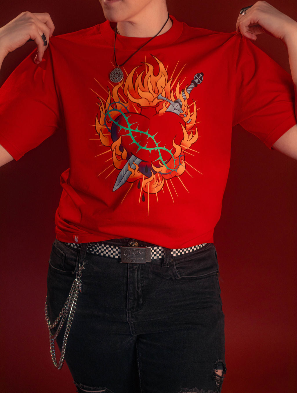 Fire red cotton tshirt with a full-color print on the front featuring the custom yellow, orange, teal, and silver flaming heart graphic with dagger and thorns. Printed collar tag information, and Saints & Sonnets logo hem tag.