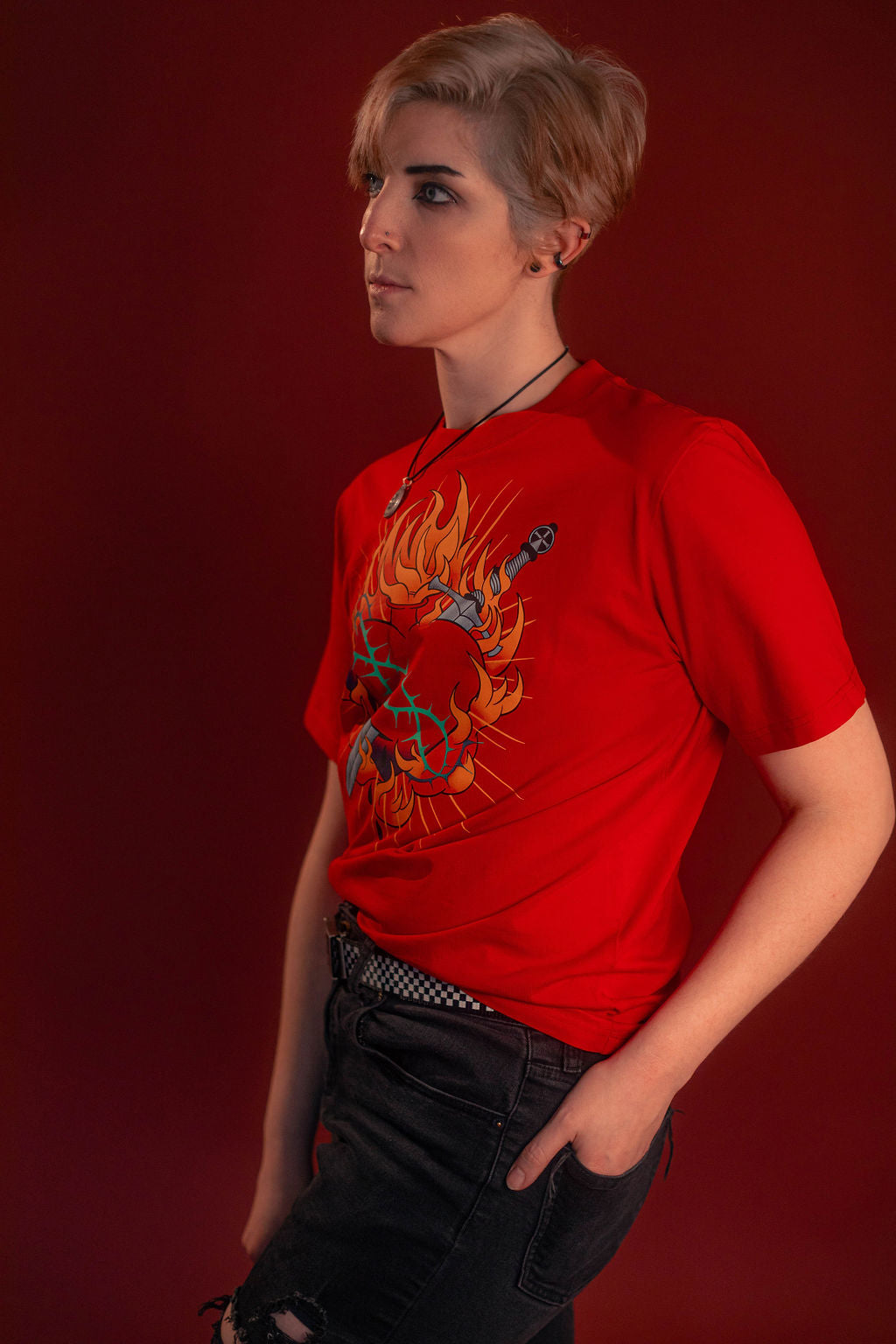 Fire red cotton tshirt with a full-color print on the front featuring the custom yellow, orange, teal, and silver flaming heart graphic with dagger and thorns. Printed collar tag information, and Saints & Sonnets logo hem tag.