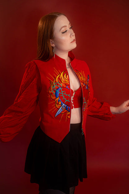 Vibrant red cotton twill vest with zipper front closure and O ring silver zipper. Large, full color orange, yellow, teal, blue, and silver embroidered sacred heart design on chest. Grey and black checkered lining and inner pocket.