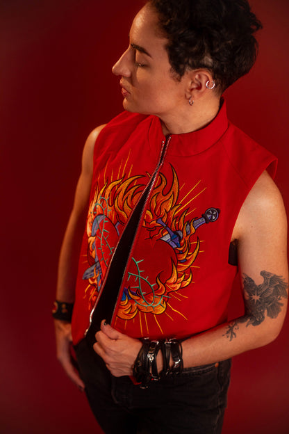 Vibrant red cotton twill vest with zipper front closure and O ring silver zipper. Large, full color orange, yellow, teal, blue, and silver embroidered sacred heart design on chest. Grey and black checkered lining and inner pocket.