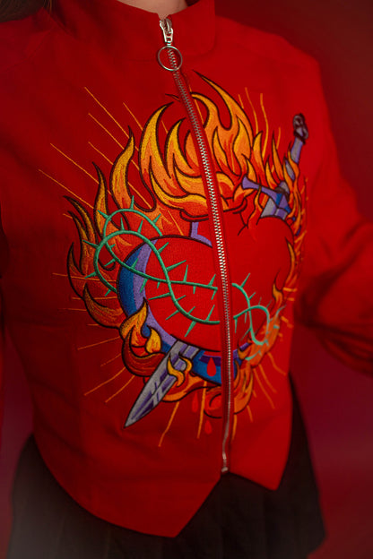 Vibrant red cotton twill vest with zipper front closure and O ring silver zipper. Large, full color orange, yellow, teal, blue, and silver embroidered sacred heart design on chest. Grey and black checkered lining and inner pocket.