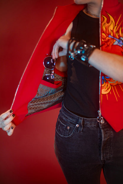 Vibrant red cotton twill vest with zipper front closure and O ring silver zipper. Large, full color orange, yellow, teal, blue, and silver embroidered sacred heart design on chest. Grey and black checkered lining and inner pocket.